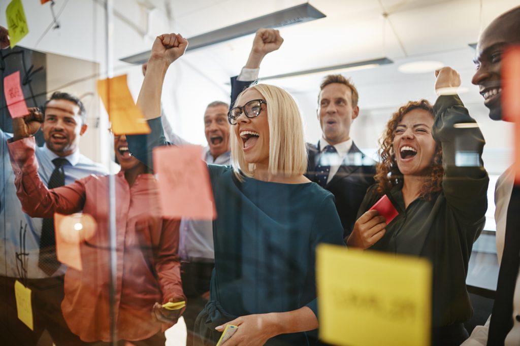 Employees at a glass wall cheering