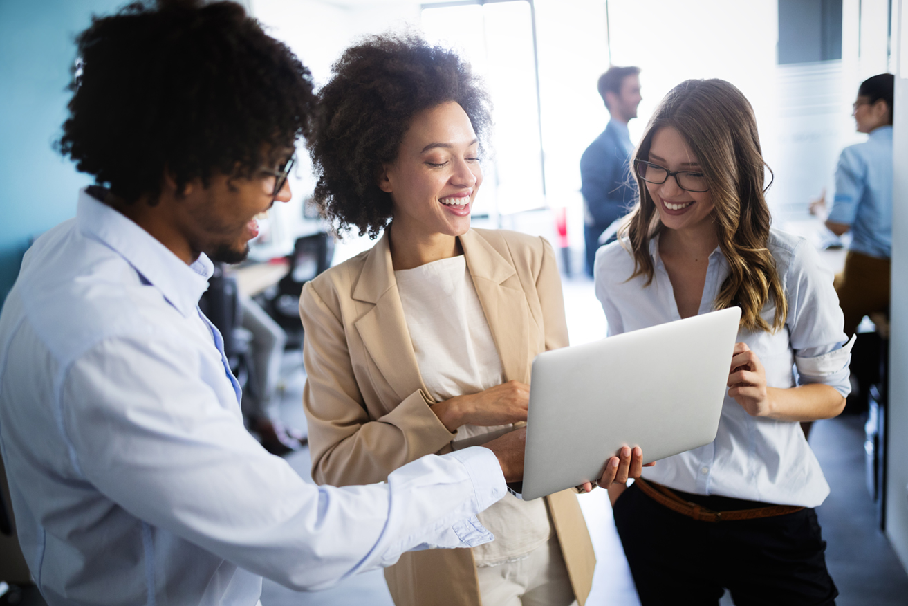 Three employees smiling at laptop screen