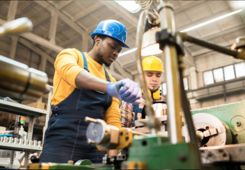 Two industrial employees working at a lathe