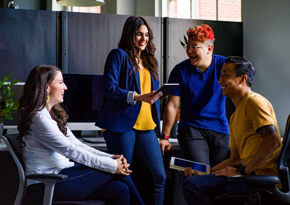 Four employees smiling and laughing in an office